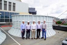 five men stand on a building roof in front of water system tank